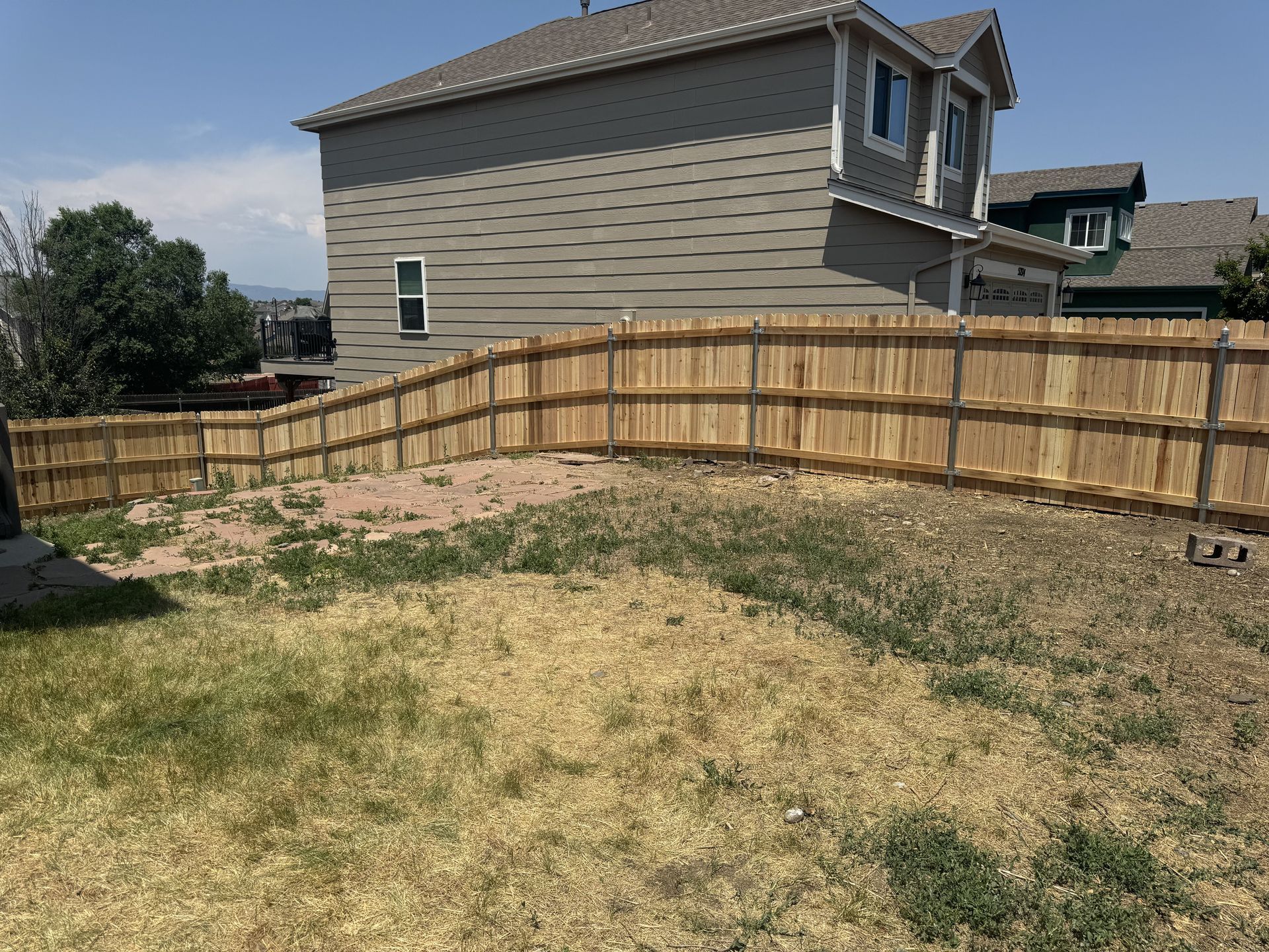 There is a wooden fence in the backyard of a house.