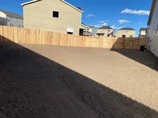 There is a wooden fence in the backyard of a house.