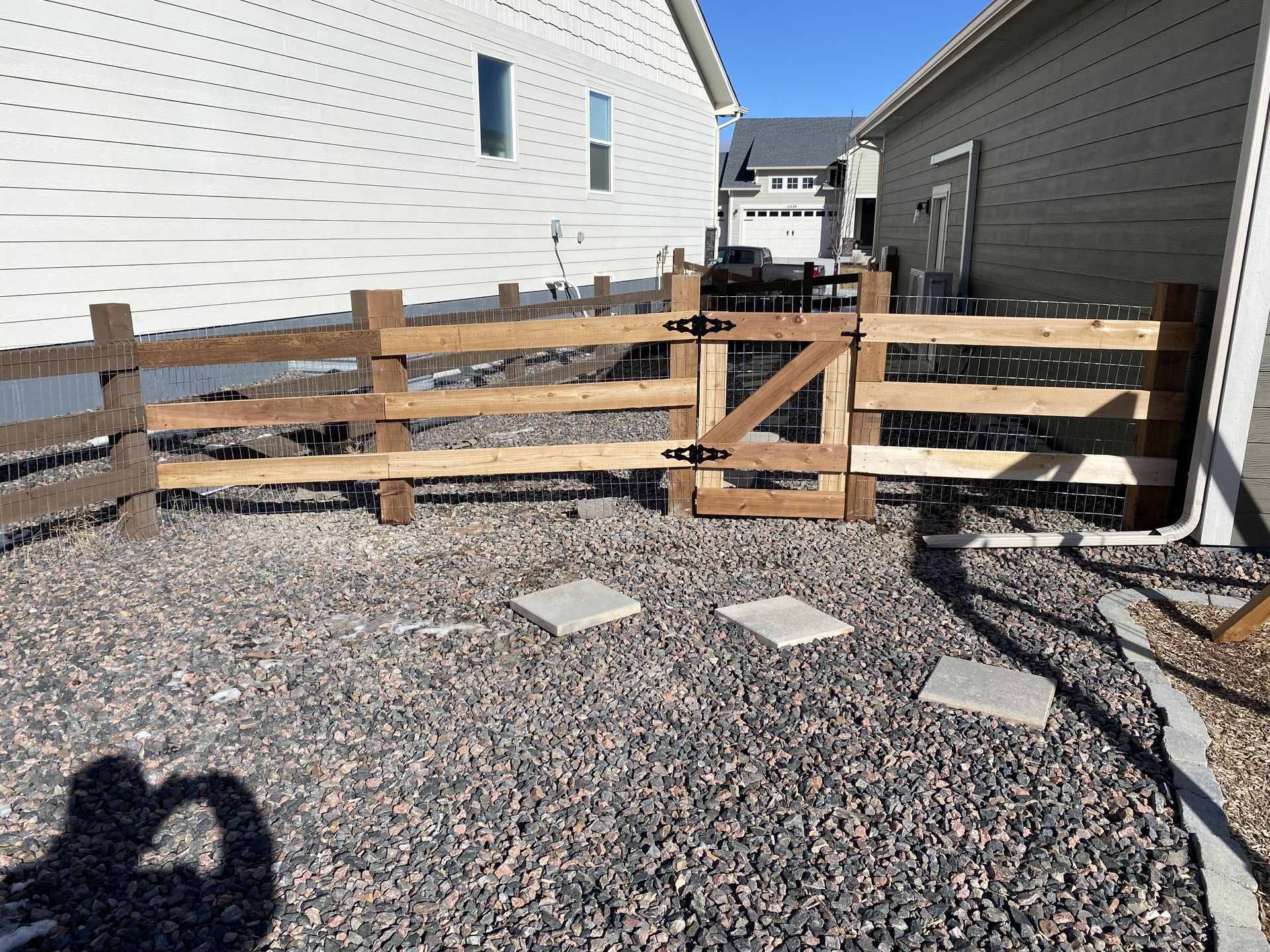 A wooden fence with a gate in front of a house.