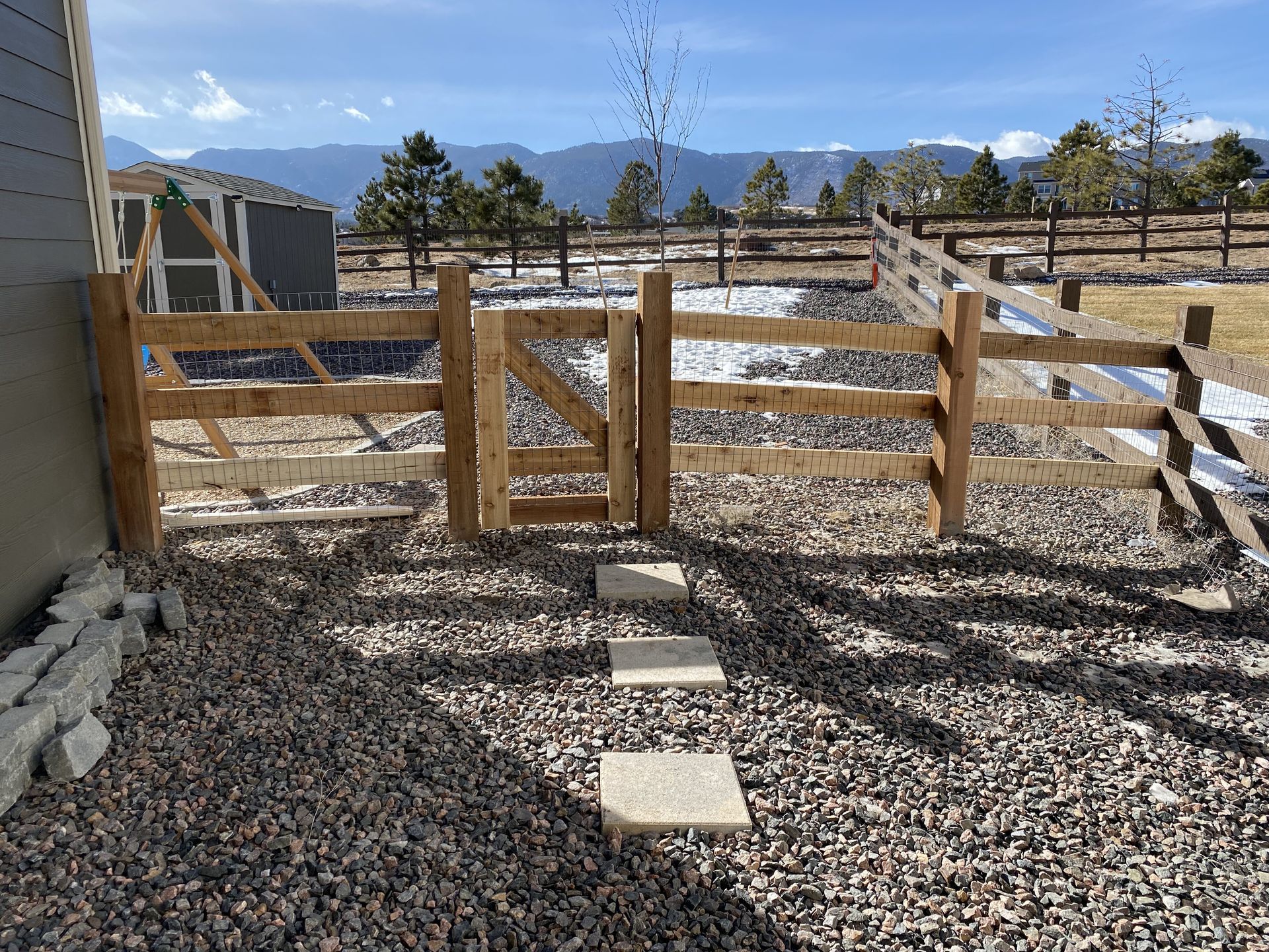 A wooden fence with a gate in the backyard of a house.