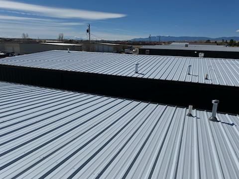 An aerial view of a metal roof with a blue sky in the background.