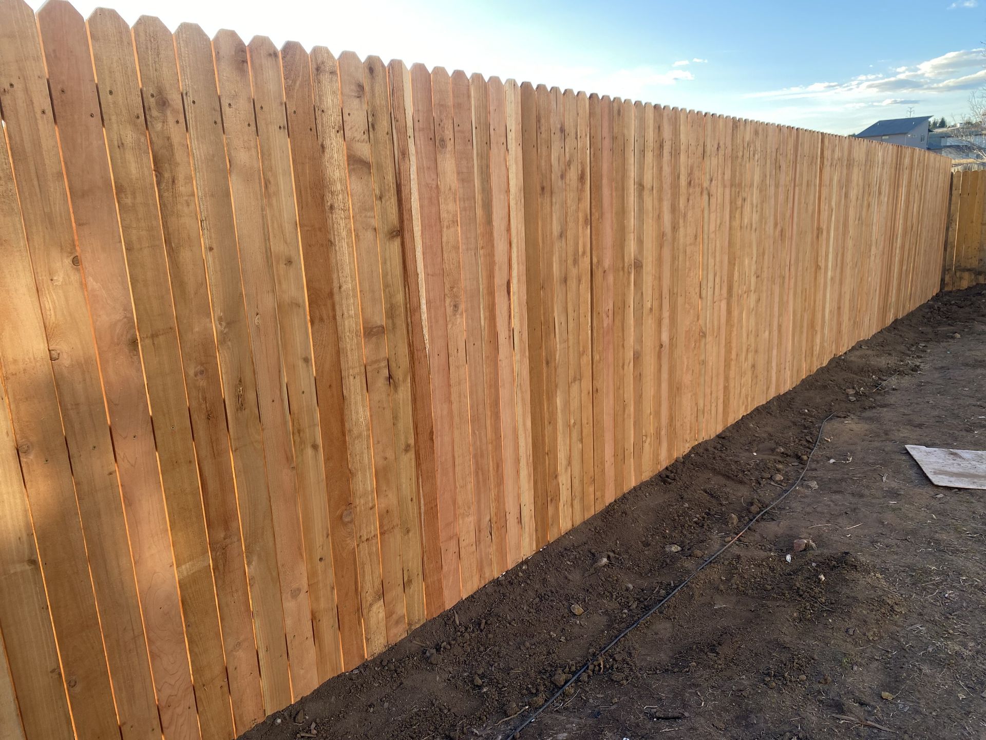 A wooden fence is sitting on top of a dirt field.