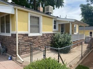 A yellow house with a stone wall and a fence in front of it.