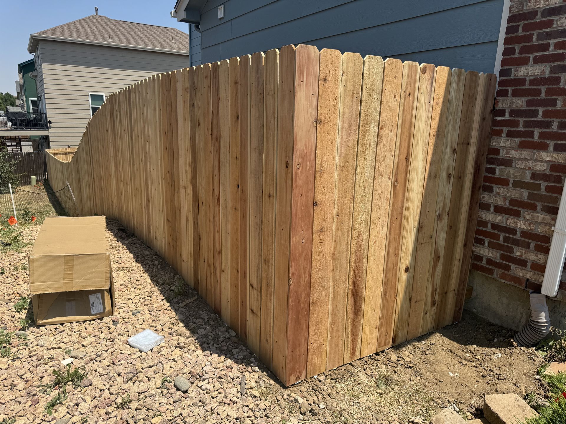 A wooden fence is sitting in front of a brick house.