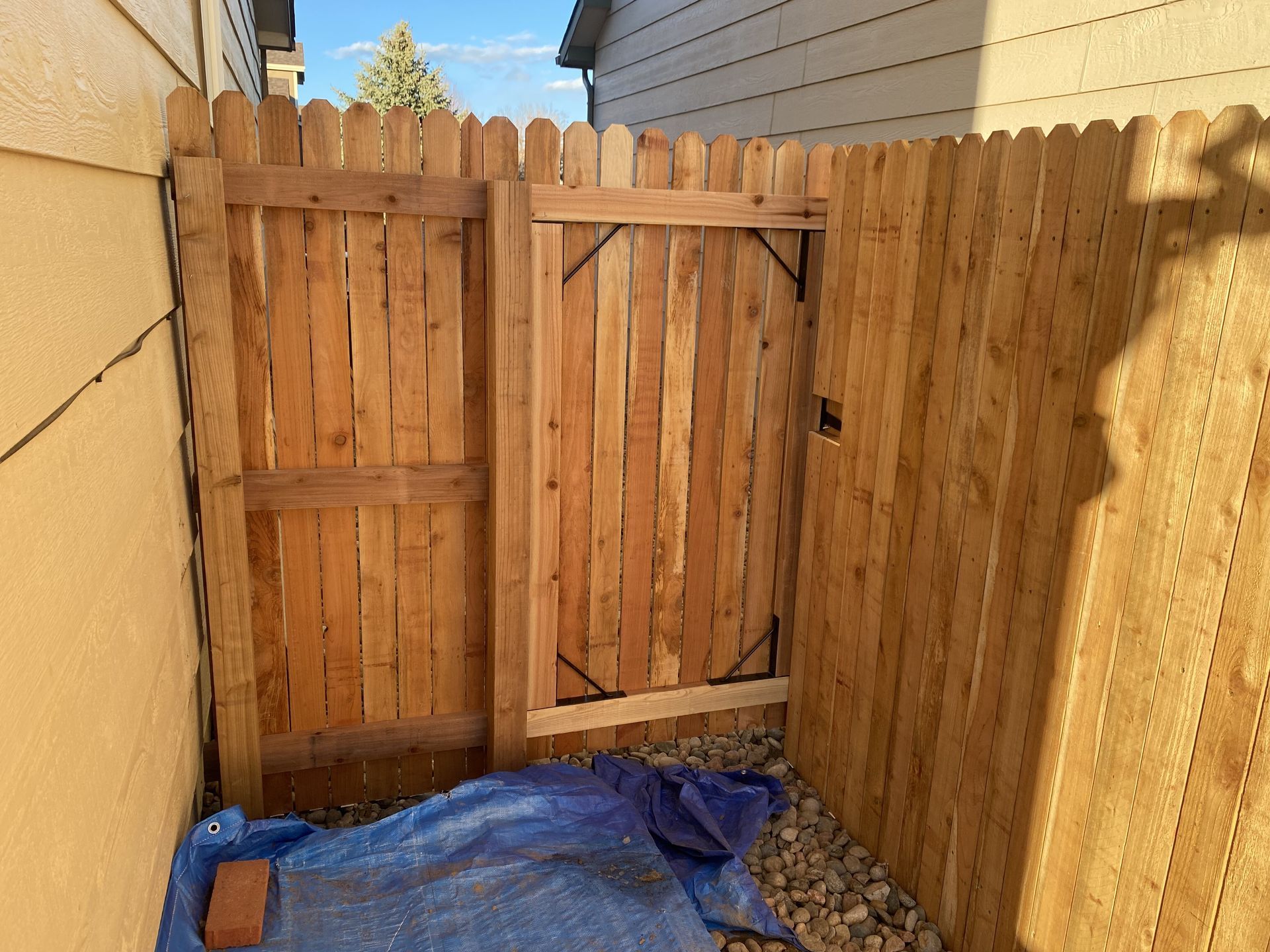 A wooden fence with a gate in the backyard of a house.