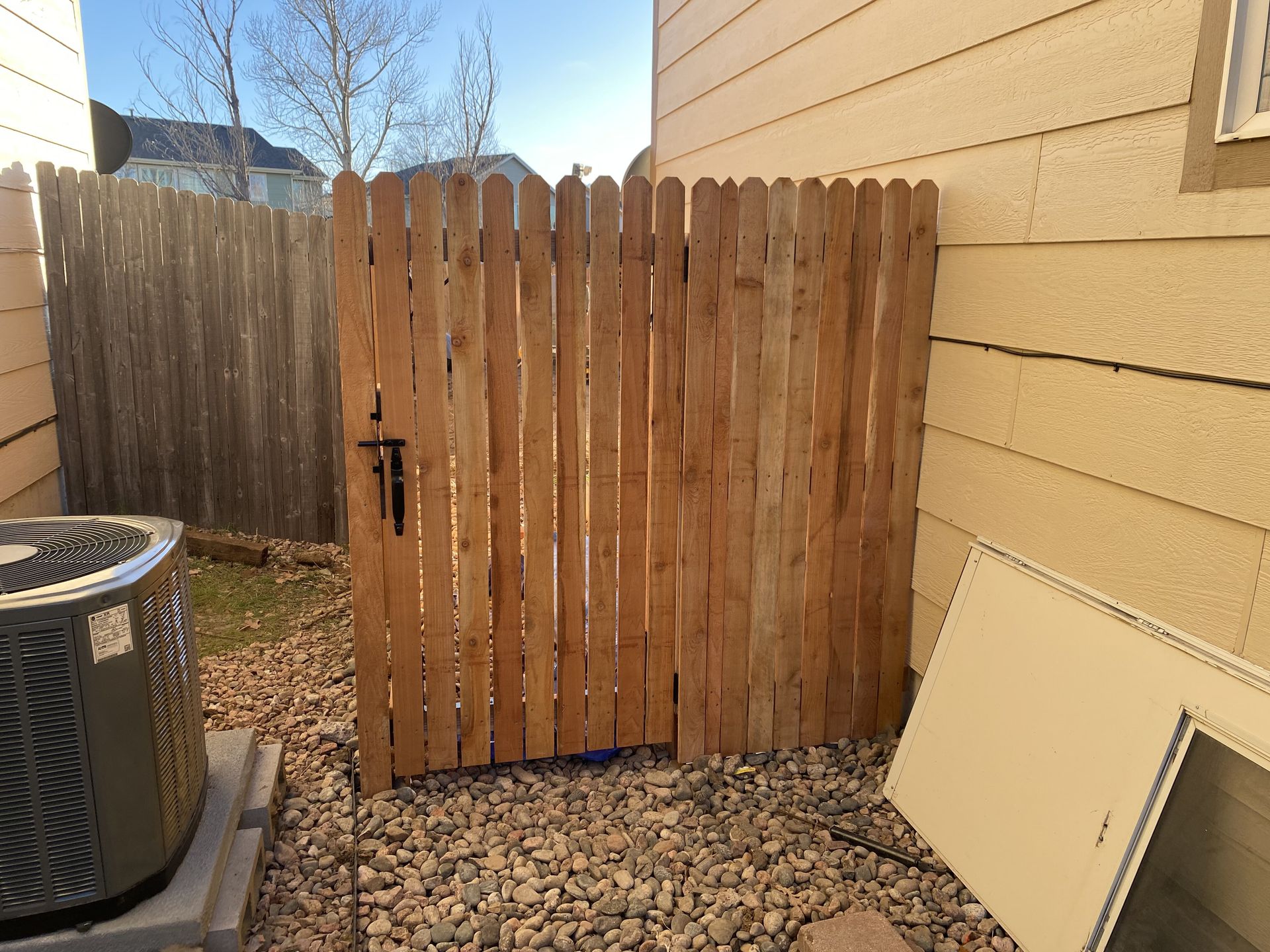 A wooden fence with a gate in the backyard of a house.