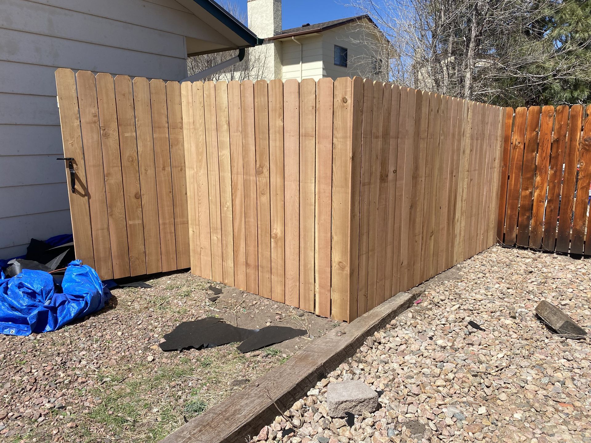 A wooden fence is being built in the backyard of a house.