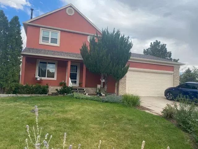A red house with a car parked in front of it.