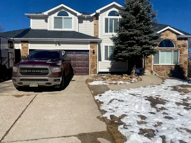 A ram truck is parked in front of a large house.