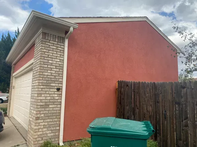 A red garage with a green trash can in front of it