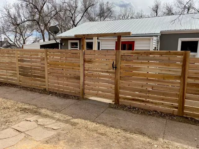 A wooden fence with a gate in front of a house.