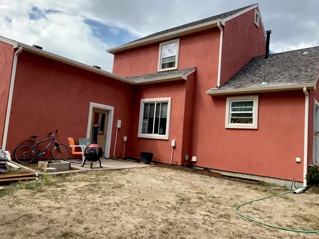 A red house with a lot of windows is sitting on top of a dirt field.
