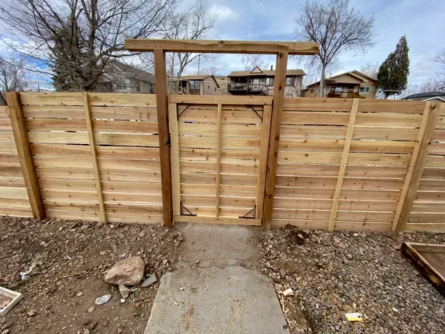 A wooden fence with a gate in the middle of it.