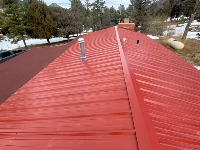 A red metal roof with a chimney on top of it.