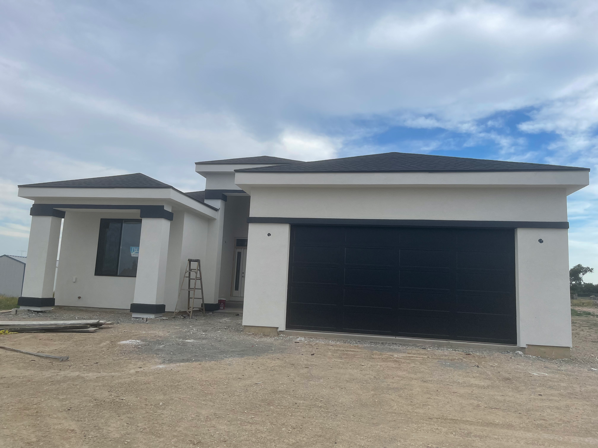 A white house with a black garage door is being built.