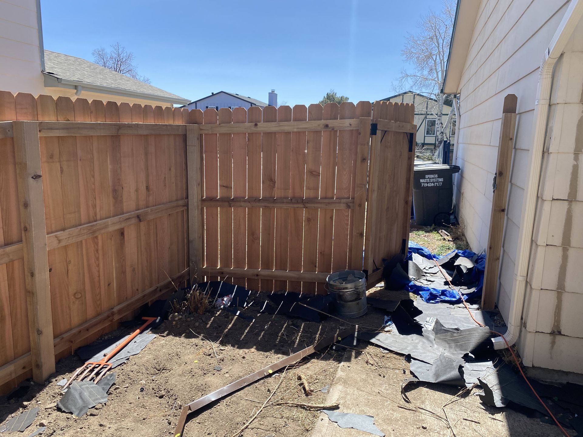 A wooden fence is being built in the backyard of a house.