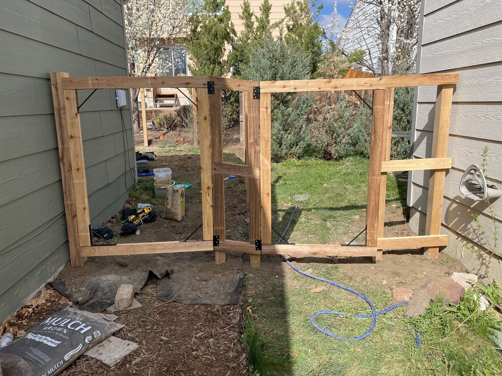 A wooden gate is being built in the backyard of a house.