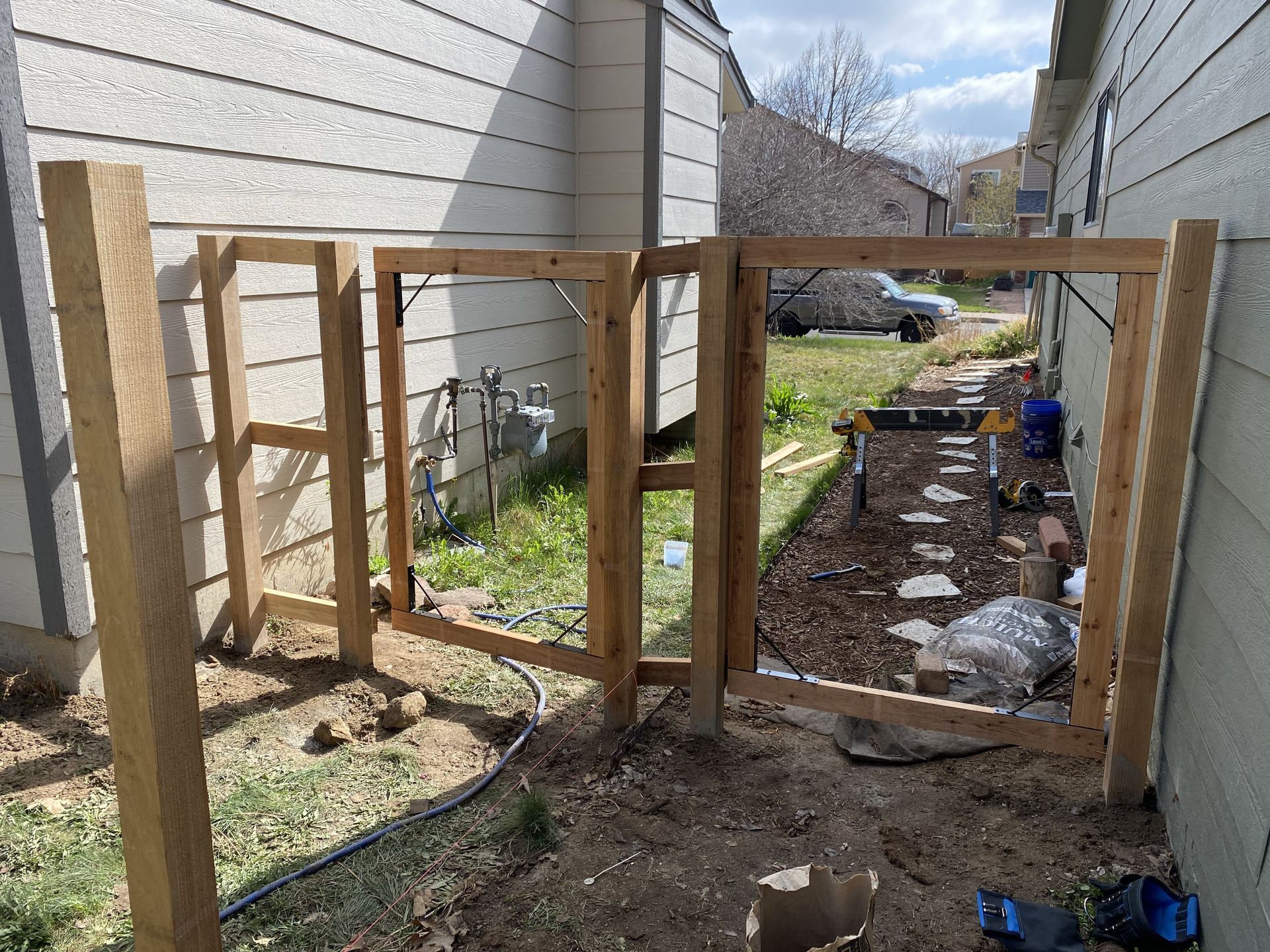 A wooden fence is being built in the backyard of a house.