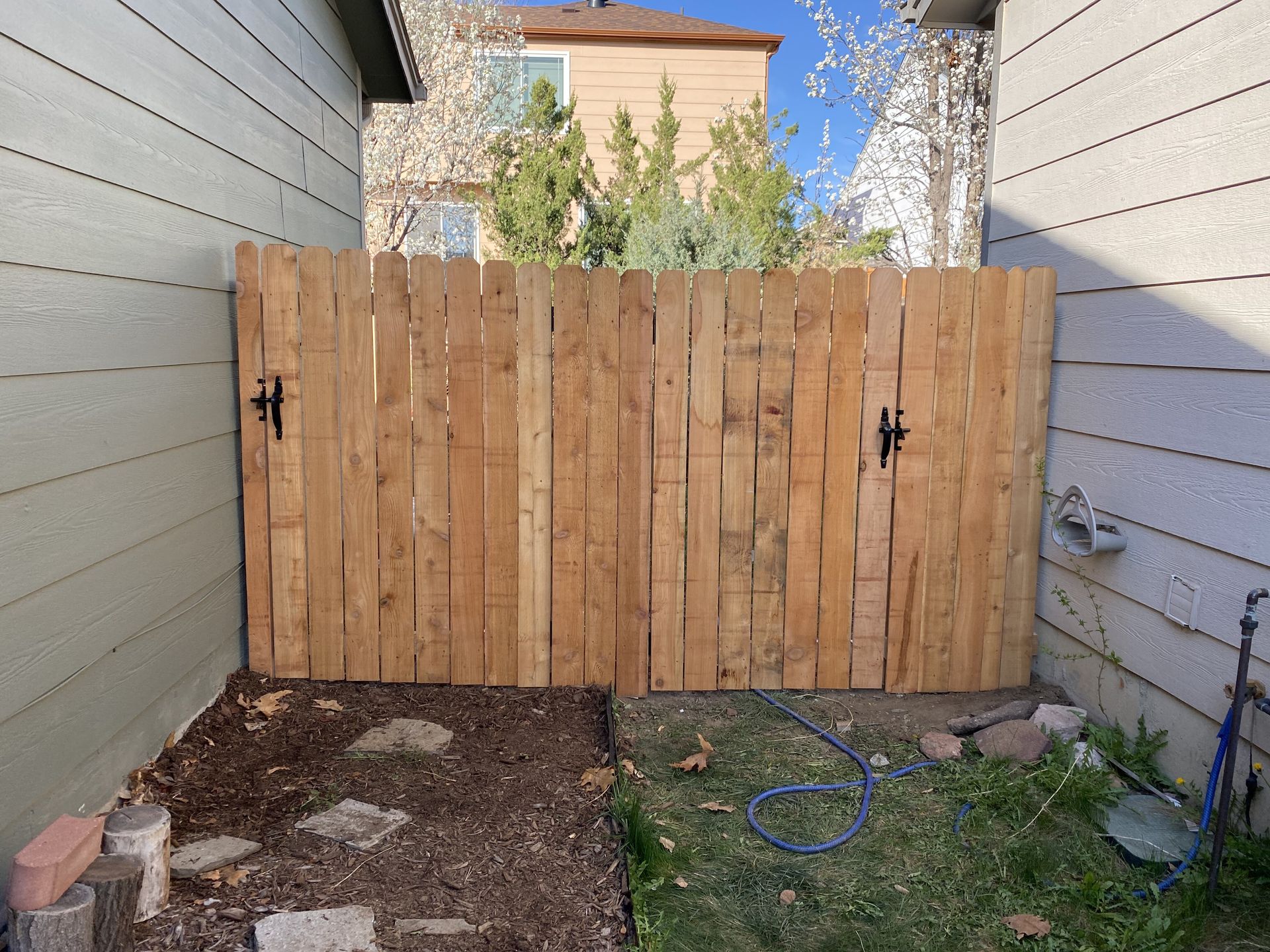 A wooden fence with a gate in the backyard of a house.