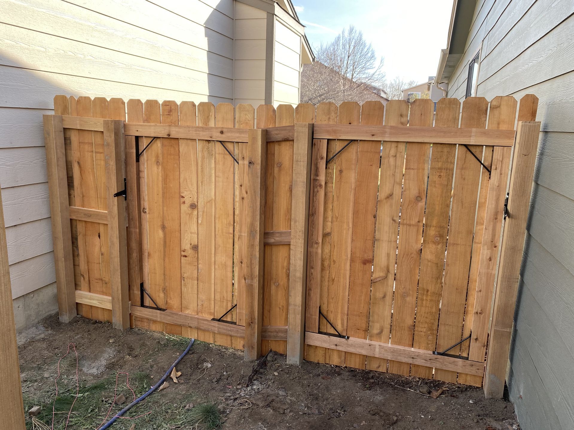 A wooden fence with a gate in the backyard of a house.