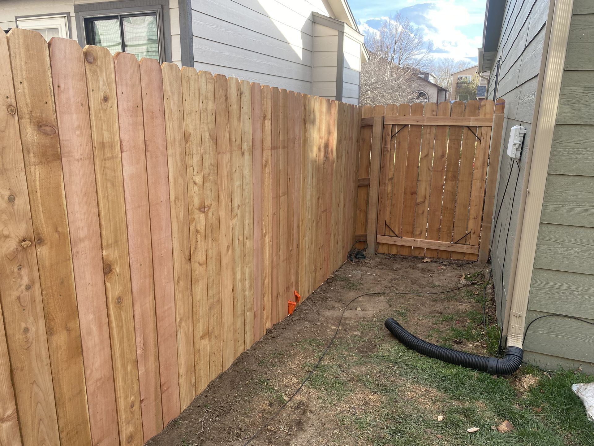 A wooden fence with a gate in the backyard of a house.