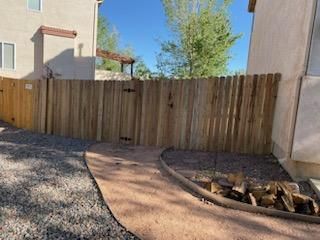 A wooden fence is in the backyard of a house.
