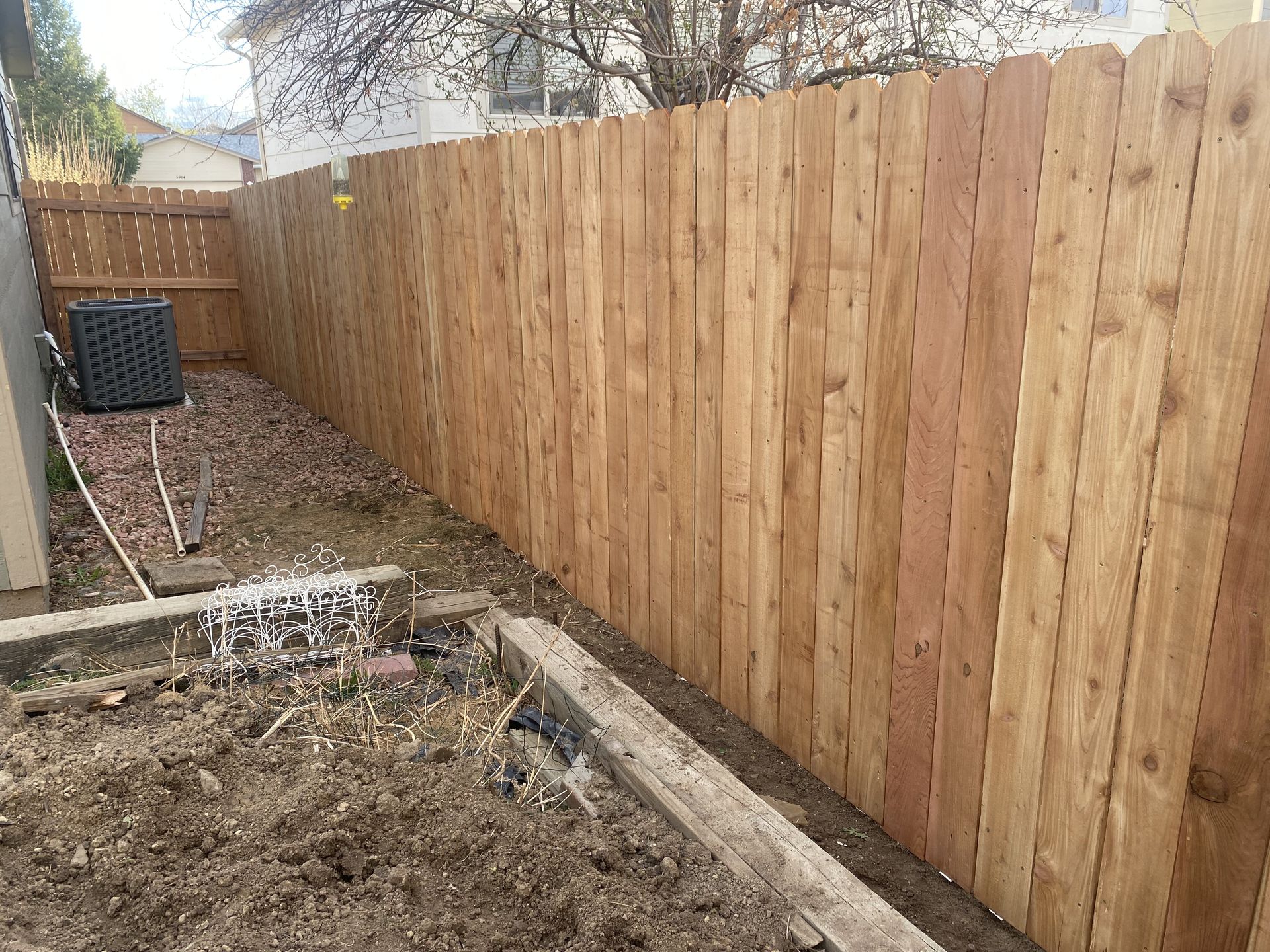 A wooden fence is in the backyard of a house.
