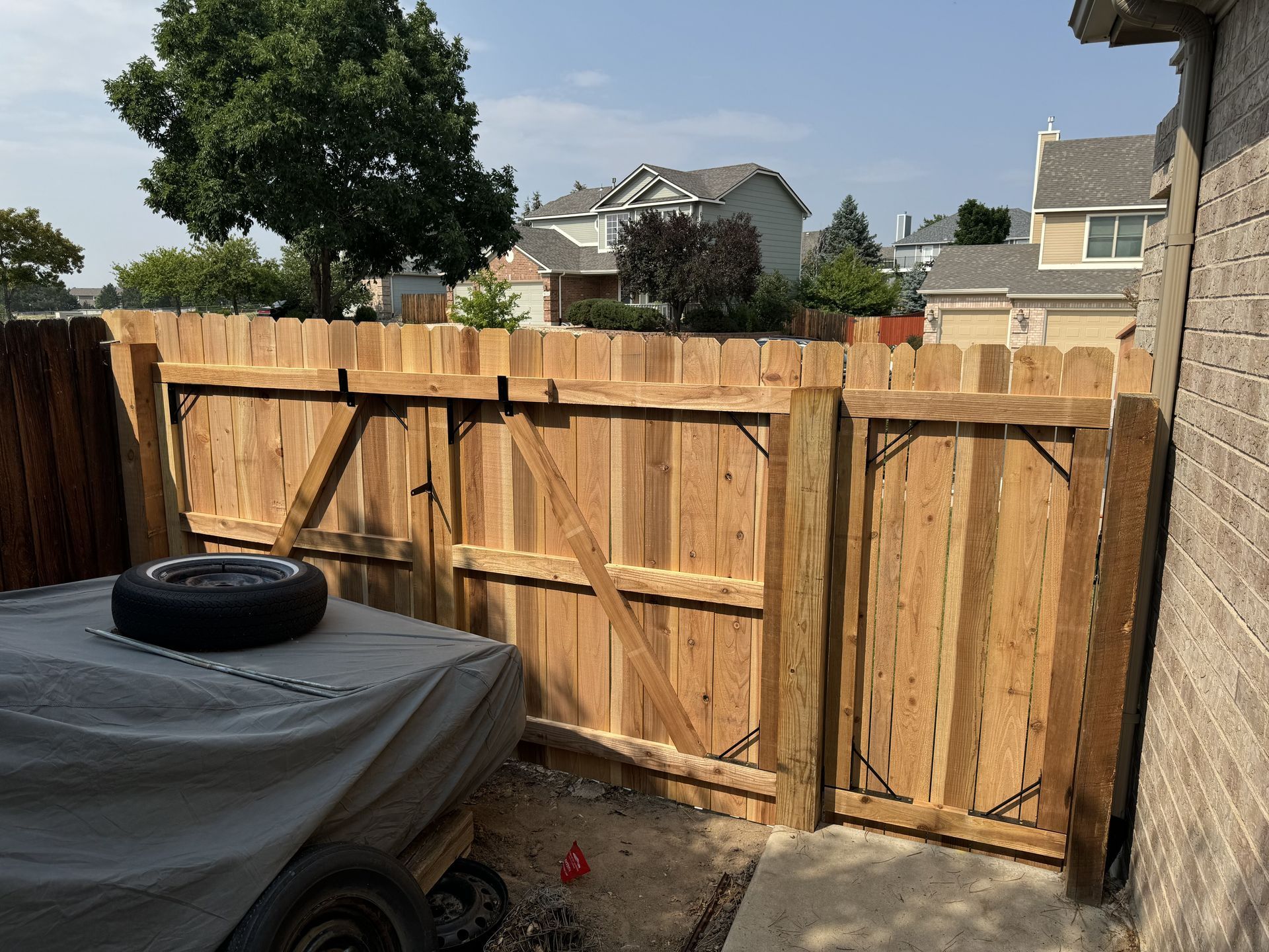 A wooden fence with a gate and a tire on top of it.