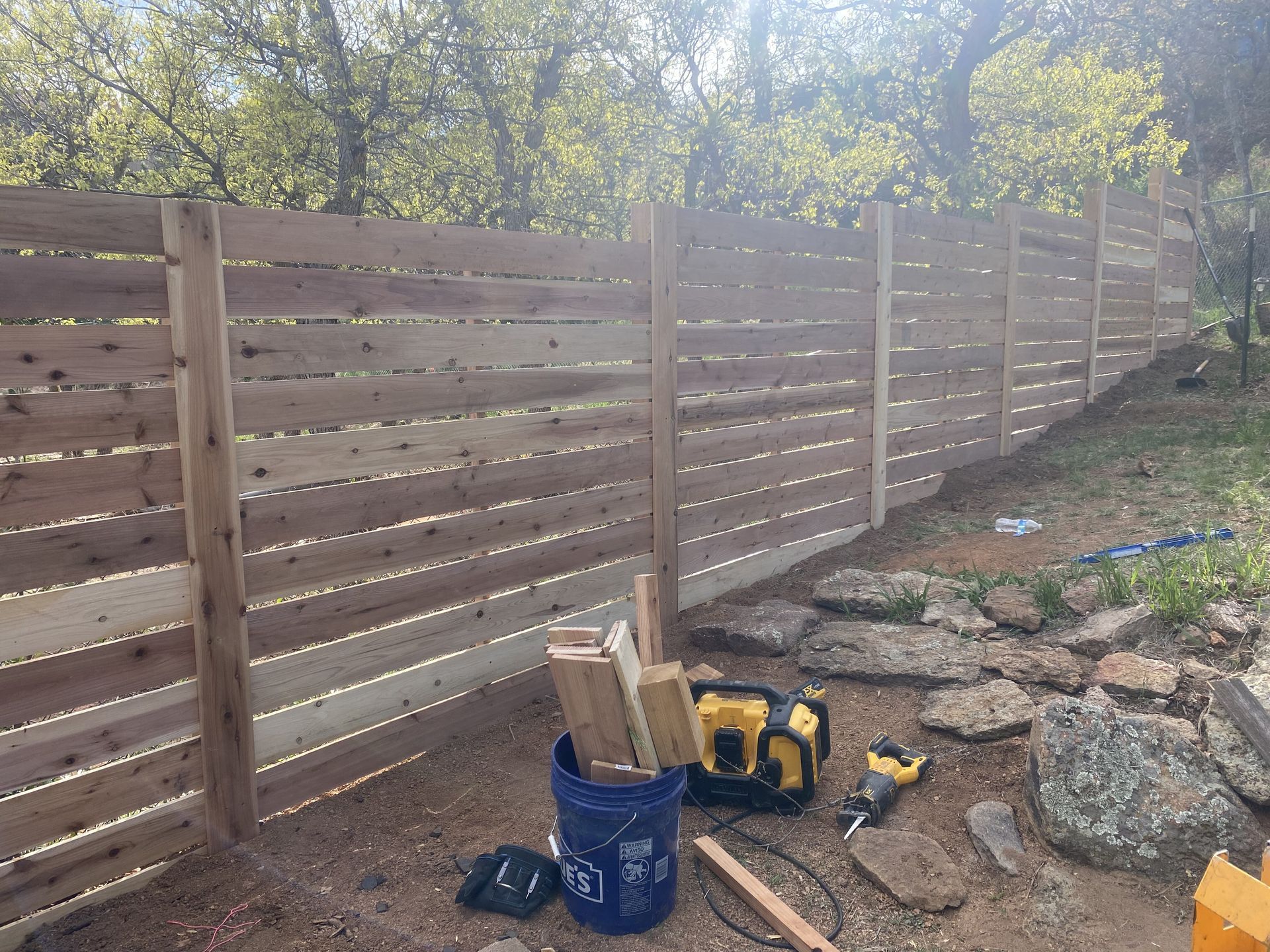 A wooden fence is being built in a backyard.