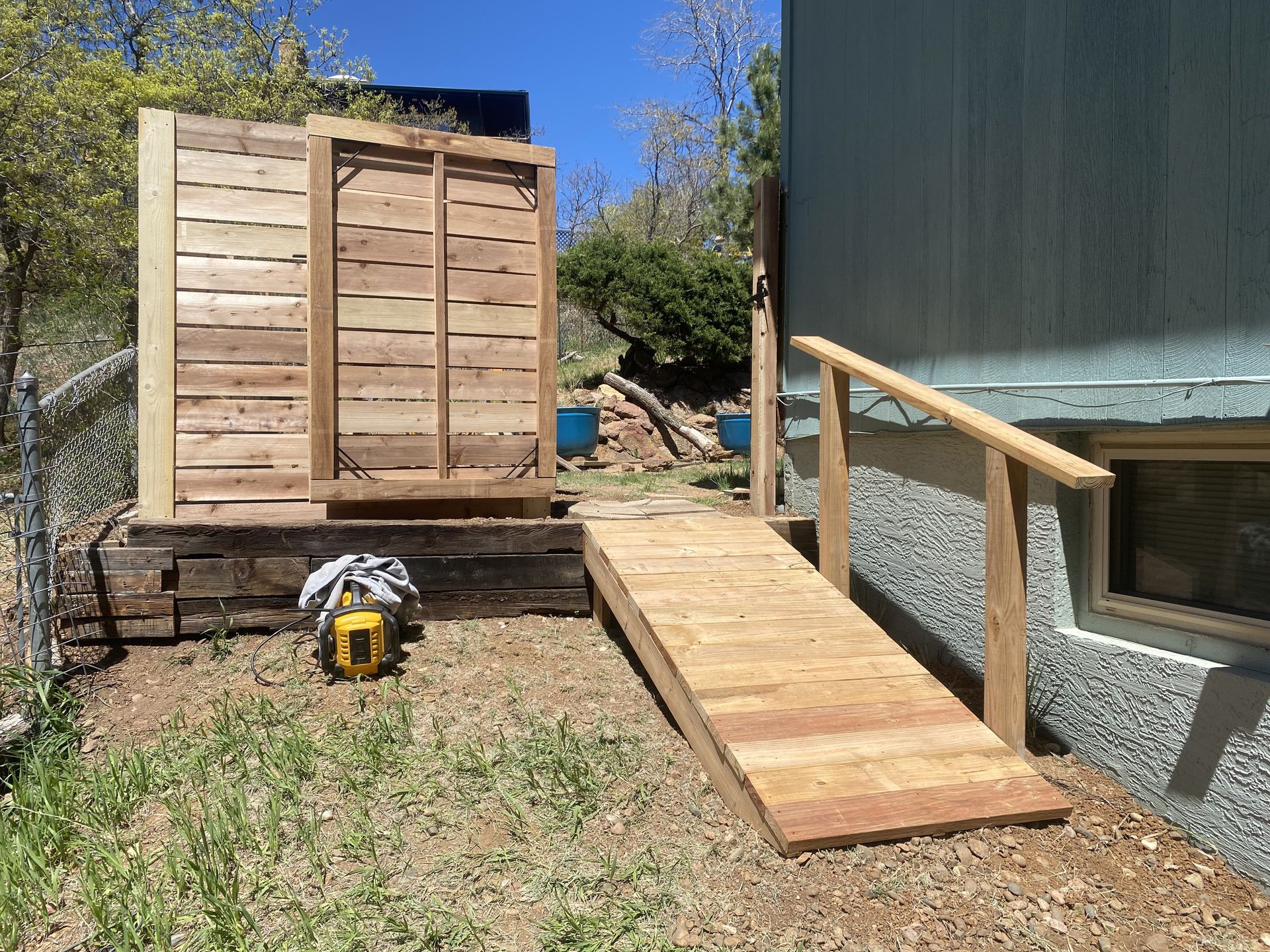 A wooden ramp leading to a shed in the backyard
