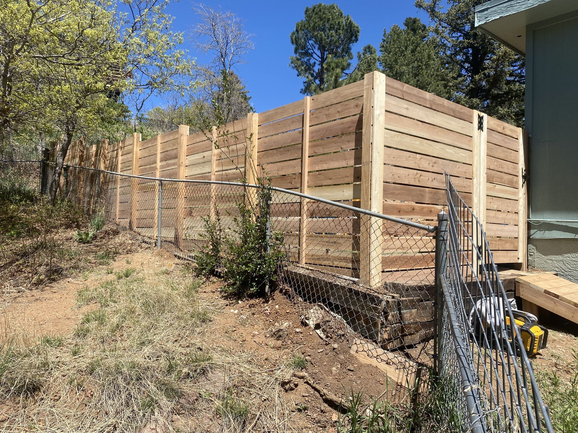 A wooden fence is being built in the backyard of a house.