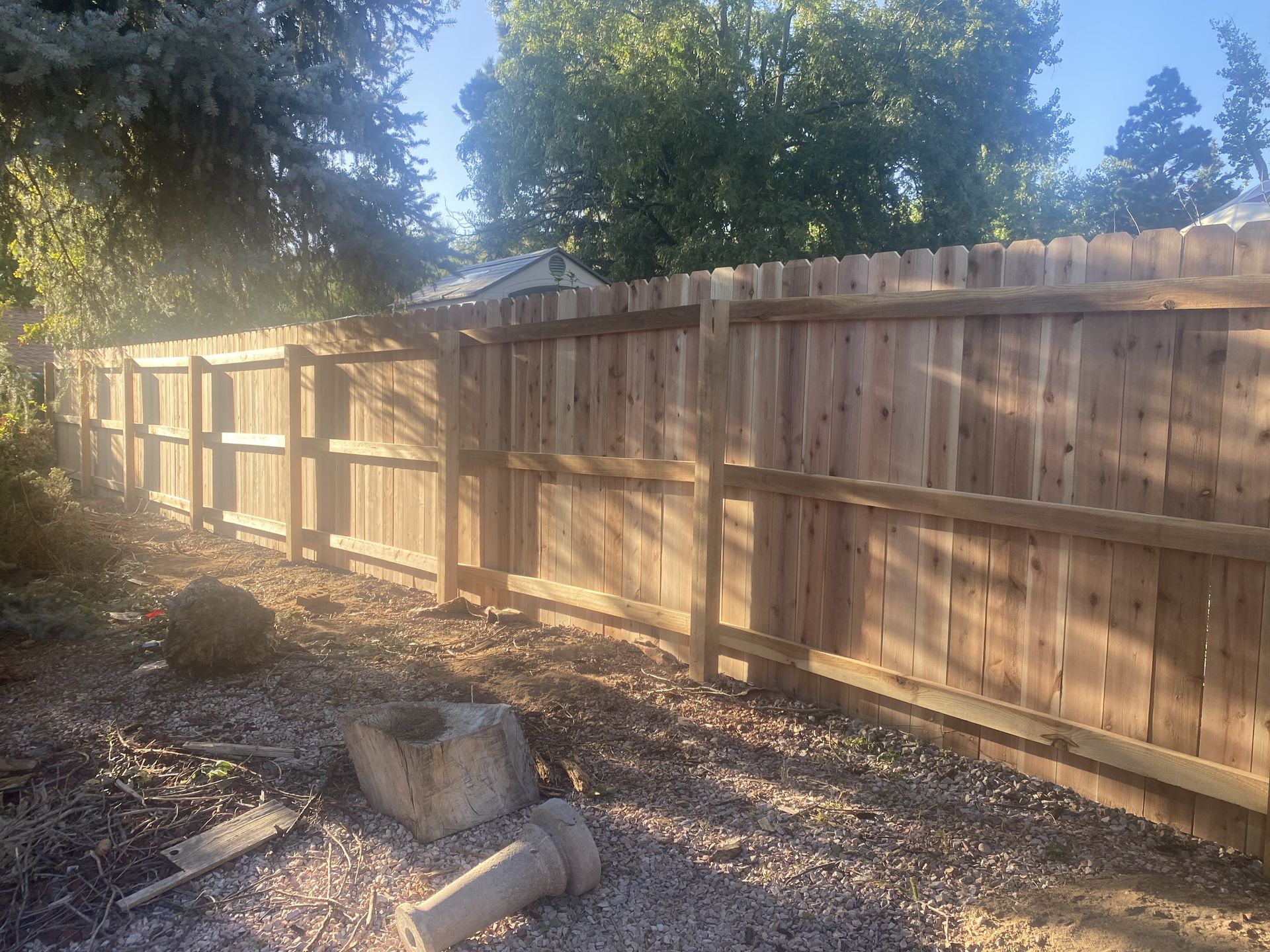 A wooden fence is being built in the backyard of a house.