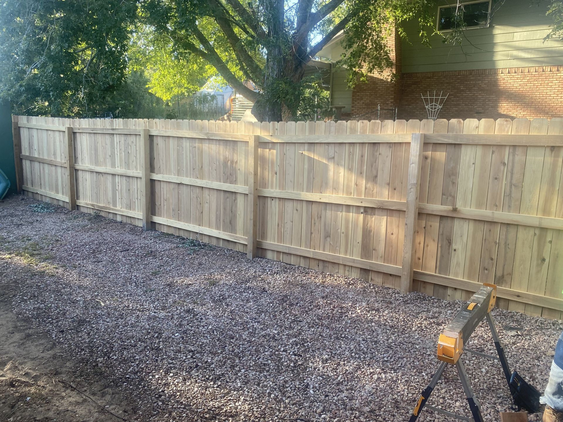 A wooden fence is being built in the backyard of a house.