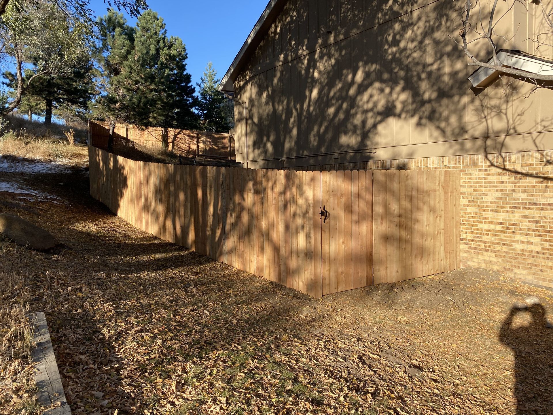 A wooden fence is in front of a brick building.