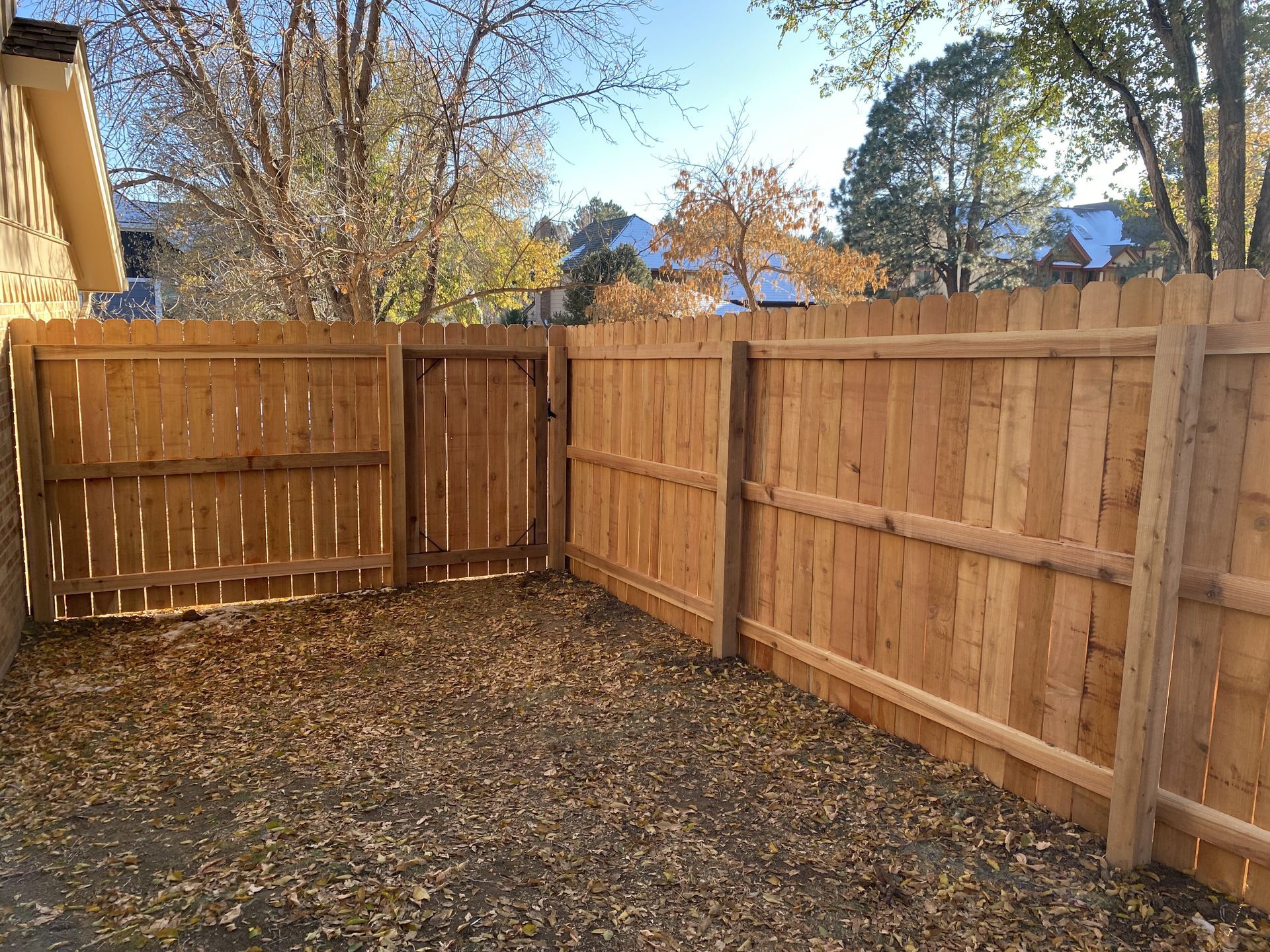 A wooden fence with a gate in the backyard of a house.