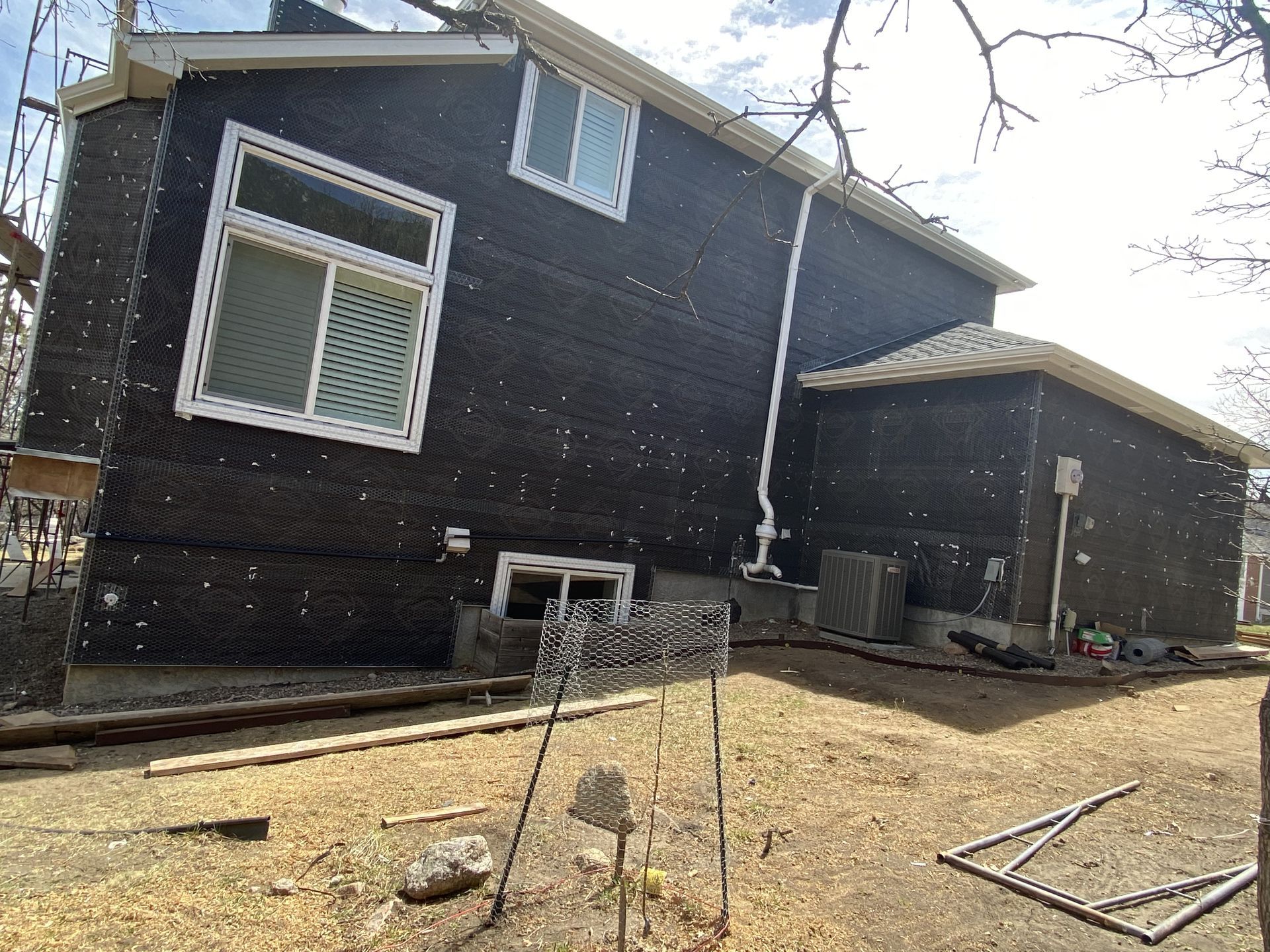 A black house with white windows is being remodeled.