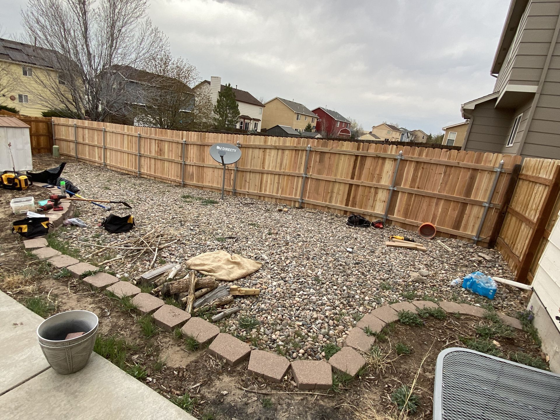 A wooden fence is being built in the backyard of a house.