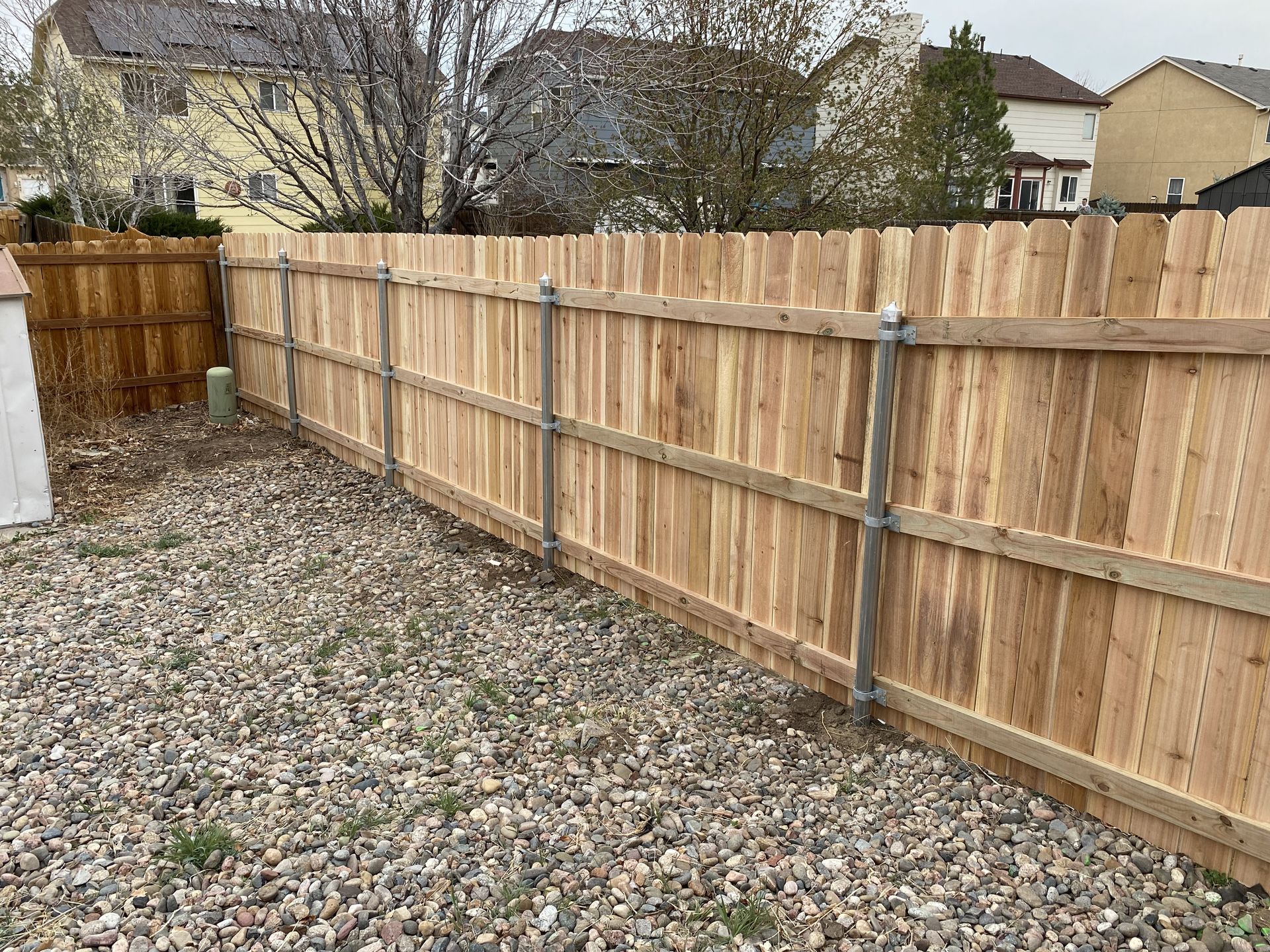 A wooden fence is sitting on top of a gravel lot.
