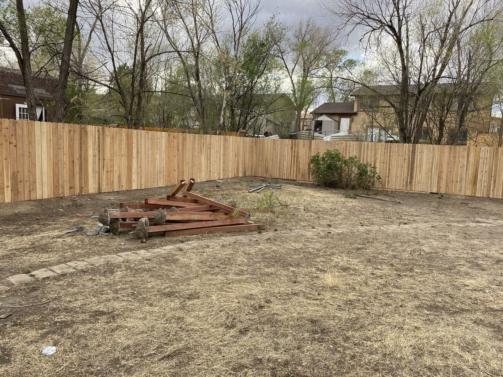 A backyard with a wooden fence and a pile of pallets.