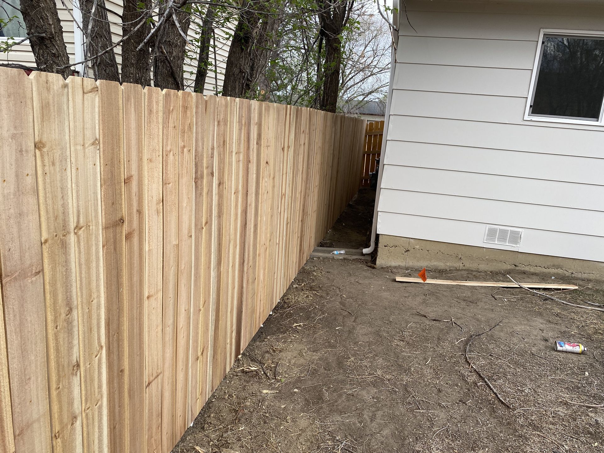 A wooden fence is along the side of a house.