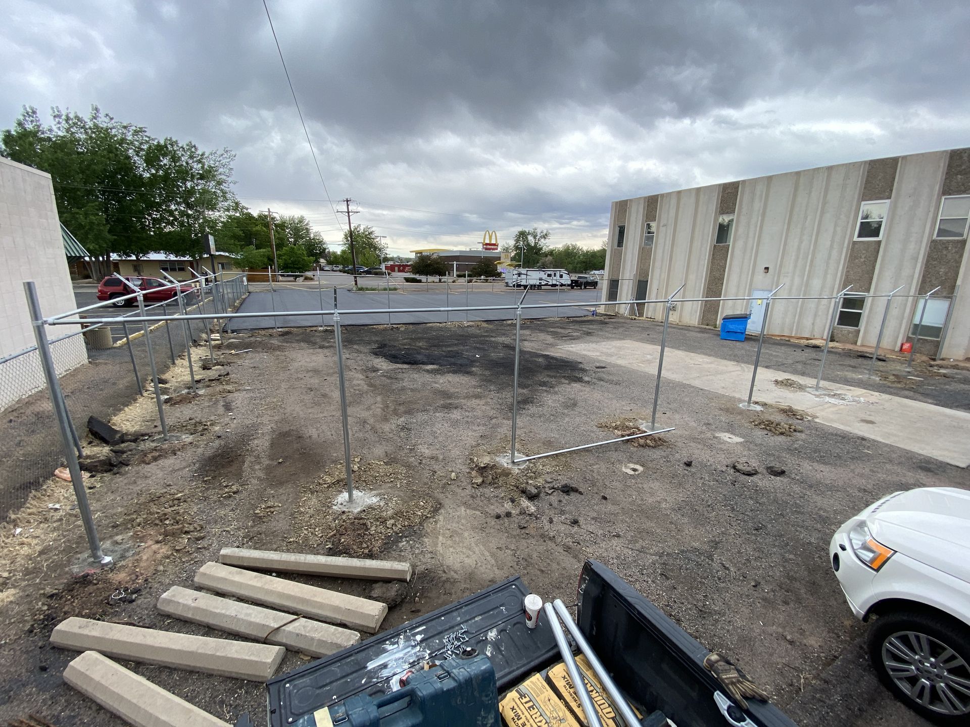 A truck is parked in a dirt lot in front of a building.