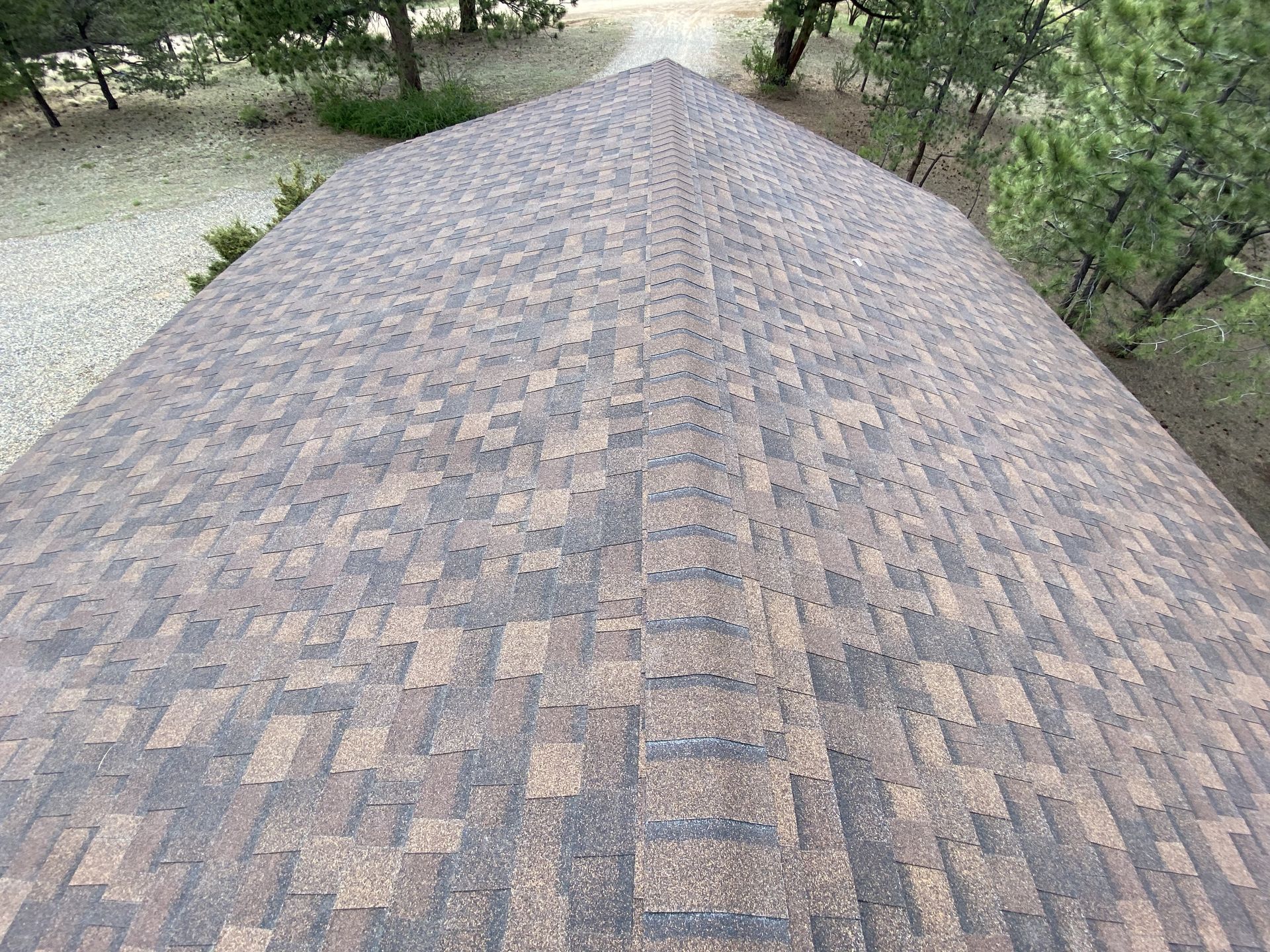 An aerial view of a roof with a lot of shingles and trees in the background.