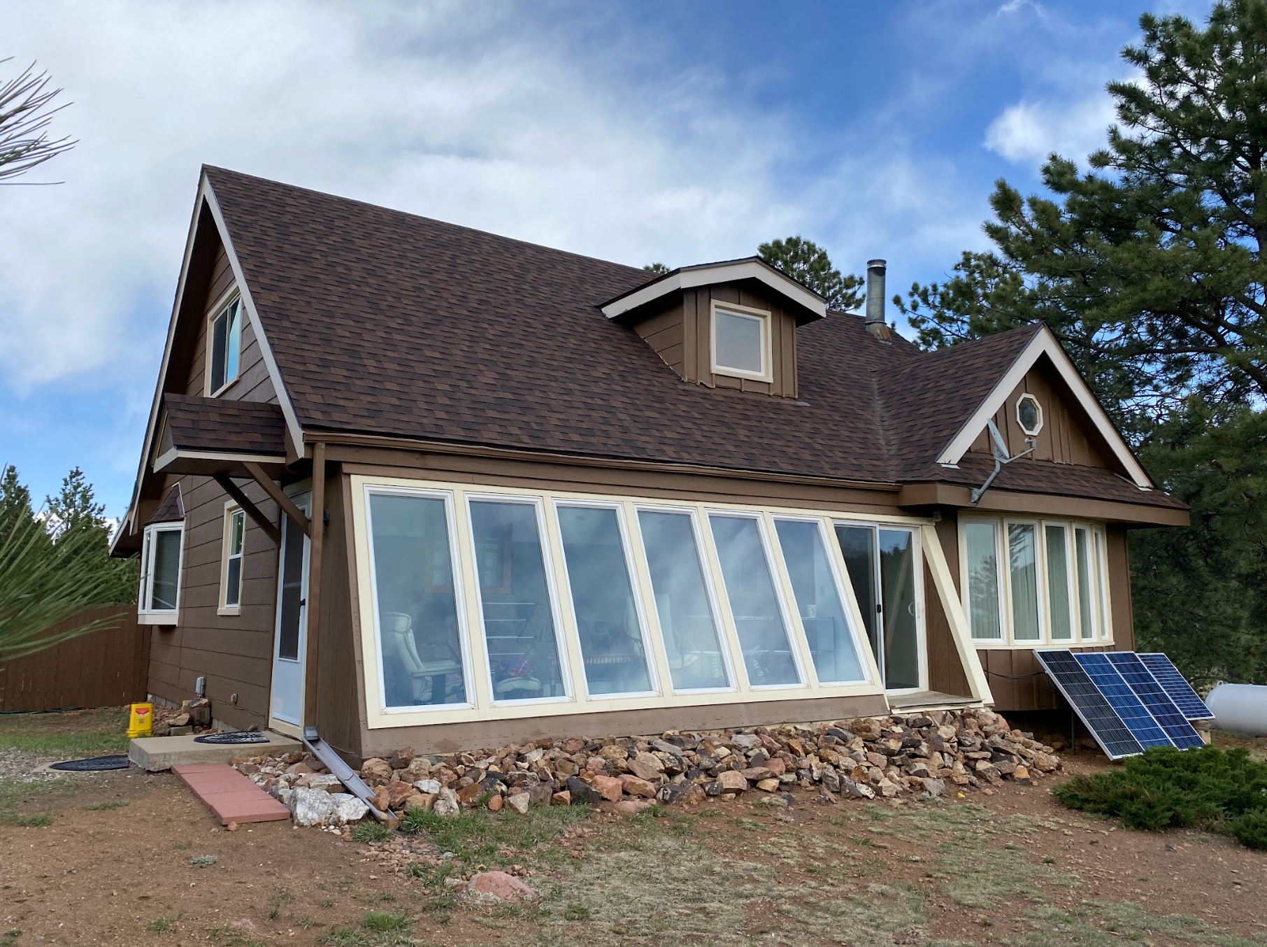 A house with a lot of windows and a solar panel on the side of it.