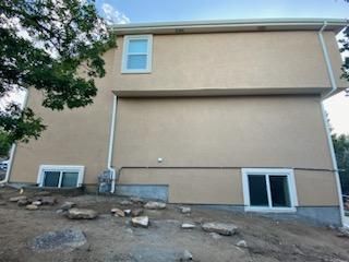 A large house with a lot of windows is sitting on top of a dirt hill.