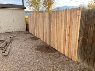 A wooden fence is in the backyard of a house.