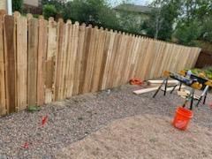 A wooden fence is being built in a backyard.
