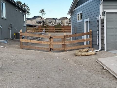 A wooden fence is in front of a house.