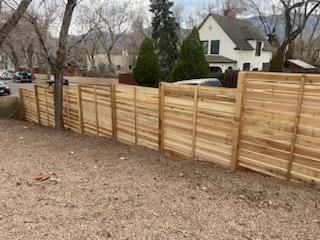 A wooden fence is in the backyard of a house.