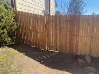 A wooden fence with a gate in the backyard of a house.