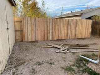 A wooden fence is being built in the backyard of a house.